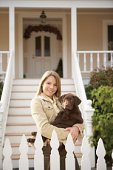 Teenage girl (14-16) holding chocolate Labrador puppy, portrait